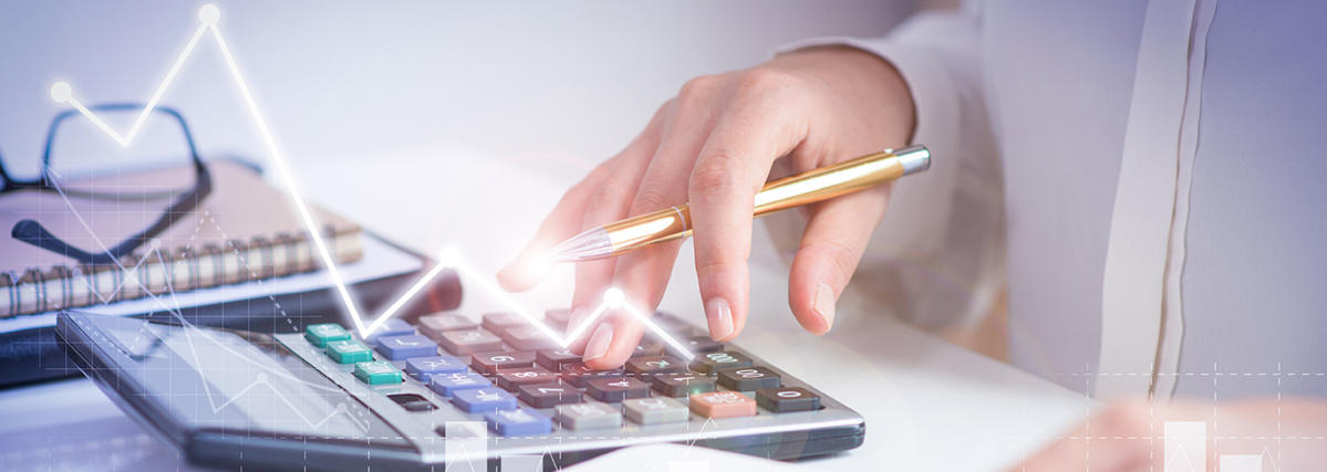 A hand holding pen, using calculator, next to the notebook