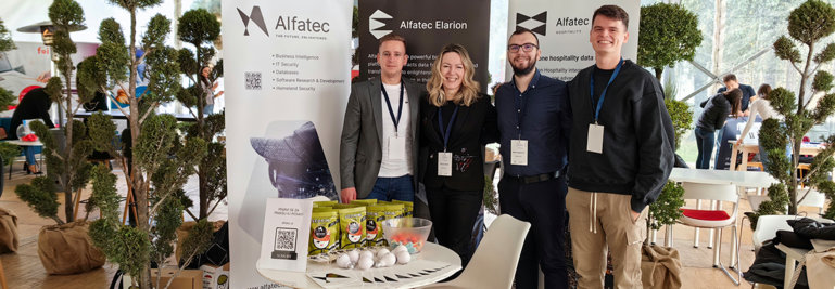 Alfatec team at the conference, standing near the table with goodies