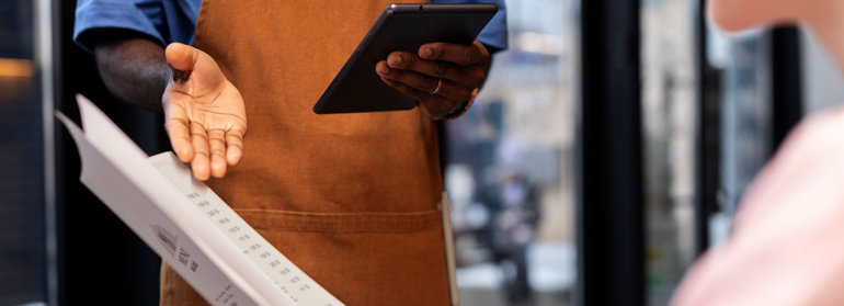 A person reading menu, and waiter showing something on it