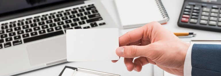 Man holding a blank card i front of the laptop